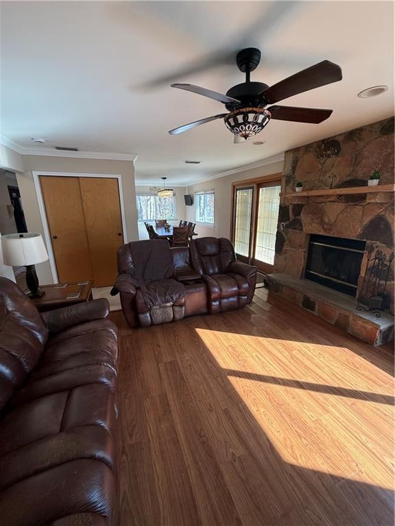 living room with ceiling fan, a fireplace, wood finished floors, and crown molding