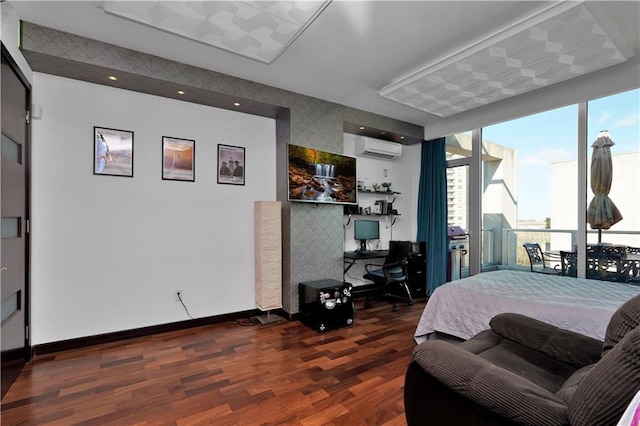 bedroom with wood finished floors, baseboards, wallpapered walls, an AC wall unit, and built in desk