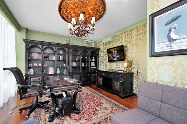 office area with wallpapered walls, an inviting chandelier, an AC wall unit, and wood finished floors