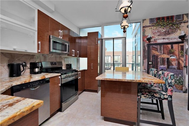 kitchen featuring light stone countertops, pendant lighting, expansive windows, a kitchen breakfast bar, and stainless steel appliances