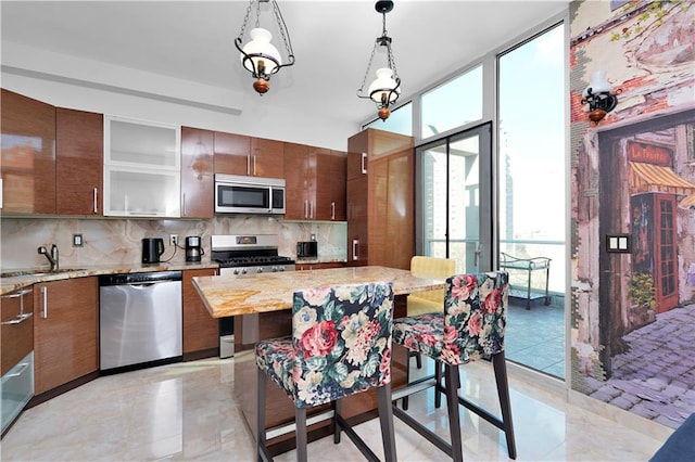 kitchen with a sink, floor to ceiling windows, tasteful backsplash, and stainless steel appliances