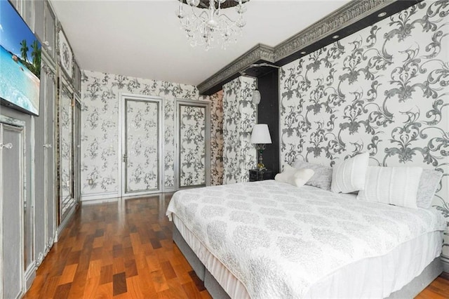 bedroom featuring a chandelier, wallpapered walls, baseboards, and wood finished floors