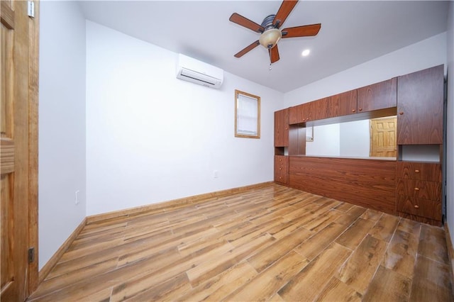 interior space featuring a wall mounted air conditioner, ceiling fan, baseboards, and wood finished floors