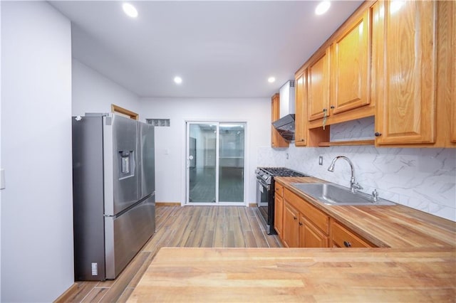 kitchen with backsplash, wood finished floors, appliances with stainless steel finishes, and a sink