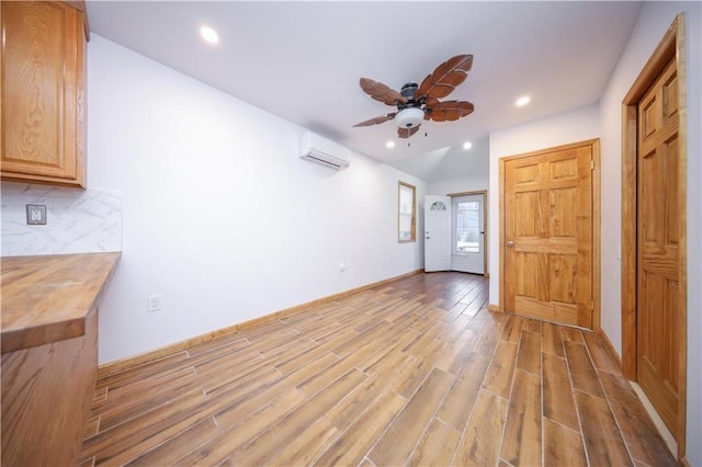 interior space with baseboards, ceiling fan, a wall mounted air conditioner, recessed lighting, and light wood-style flooring