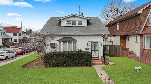 view of front of house with a shingled roof, a front yard, and stucco siding
