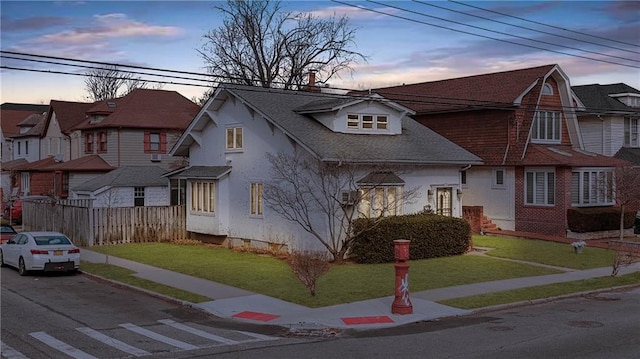view of front of home with stucco siding, a residential view, a lawn, and fence