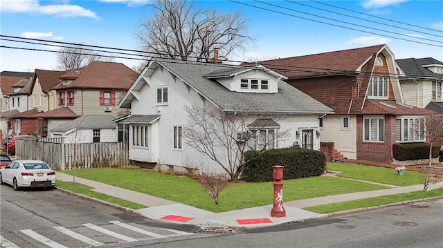 view of front of house with a residential view, fence, a shingled roof, a front yard, and stucco siding
