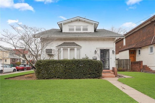 view of front of house with stucco siding, a front lawn, and a shingled roof