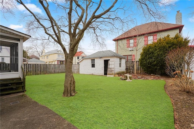 view of yard featuring a sunroom, a fenced backyard, and an outdoor structure