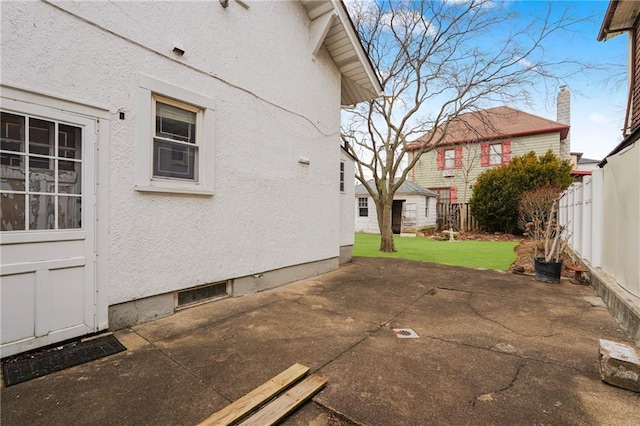view of side of property with stucco siding, fence, a chimney, and a patio