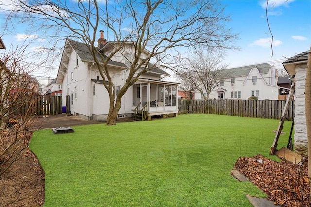 view of yard featuring a patio area, a fenced backyard, and a sunroom