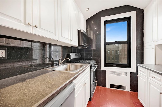 kitchen featuring dark tile patterned flooring, a sink, white cabinetry, stainless steel gas range, and radiator