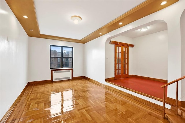 spare room with arched walkways, recessed lighting, radiator, a raised ceiling, and baseboards