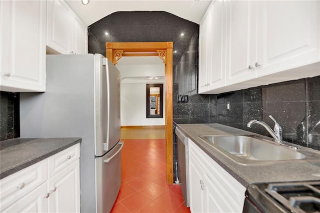 kitchen with lofted ceiling, tile patterned flooring, stainless steel appliances, a sink, and backsplash