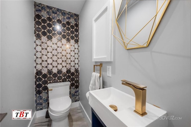 bathroom featuring toilet, baseboards, and vanity