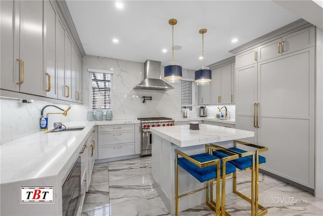 kitchen featuring high end stove, marble finish floor, wall chimney range hood, and a sink