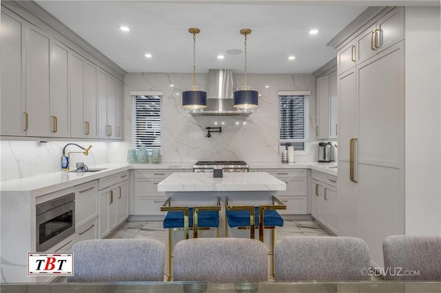 kitchen with appliances with stainless steel finishes, marble finish floor, a sink, and wall chimney range hood