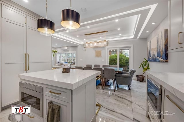 kitchen with pendant lighting, a raised ceiling, marble finish floor, and open floor plan