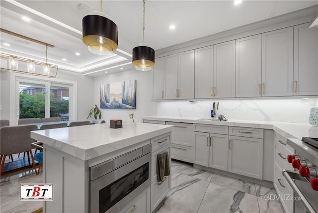 kitchen with marble finish floor, a raised ceiling, backsplash, and decorative light fixtures