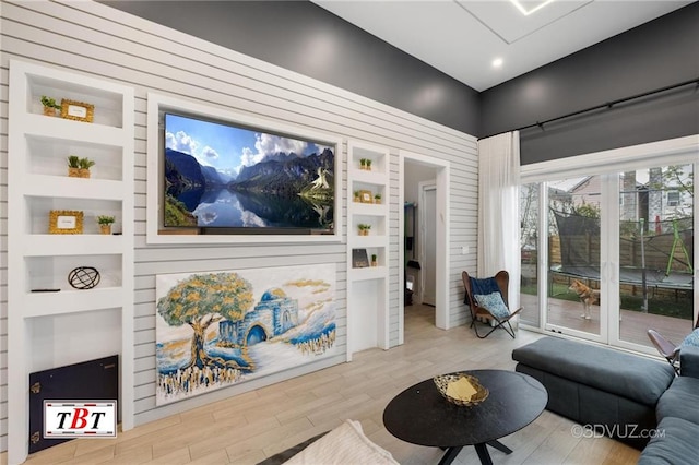 living room featuring built in shelves and wood finished floors