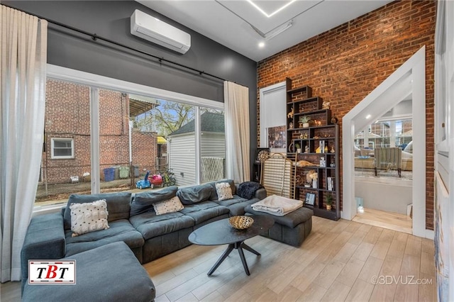 living room featuring wood finished floors, brick wall, and a wall mounted AC