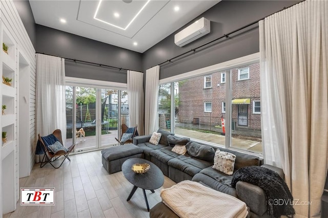 living room with a wall mounted AC, wood finished floors, and recessed lighting