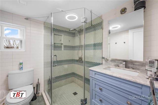 full bathroom featuring toilet, a stall shower, vanity, and tile walls