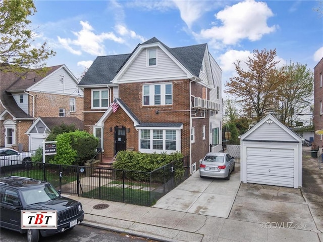 view of front facade featuring a garage, a shingled roof, a fenced front yard, an outbuilding, and brick siding