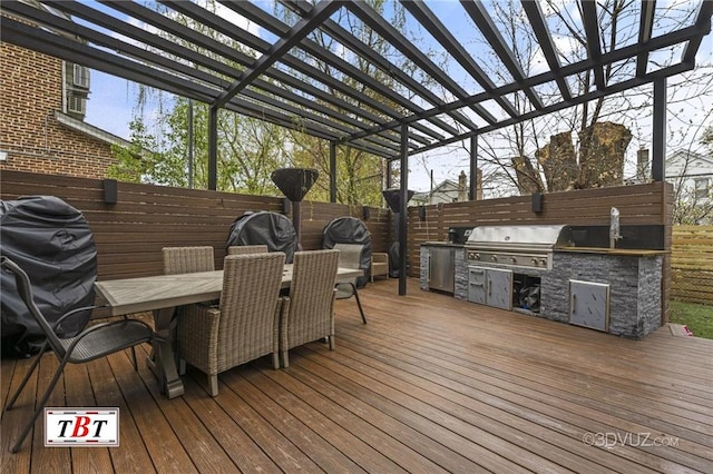 wooden terrace with outdoor dining space, fence, an outdoor kitchen, and area for grilling