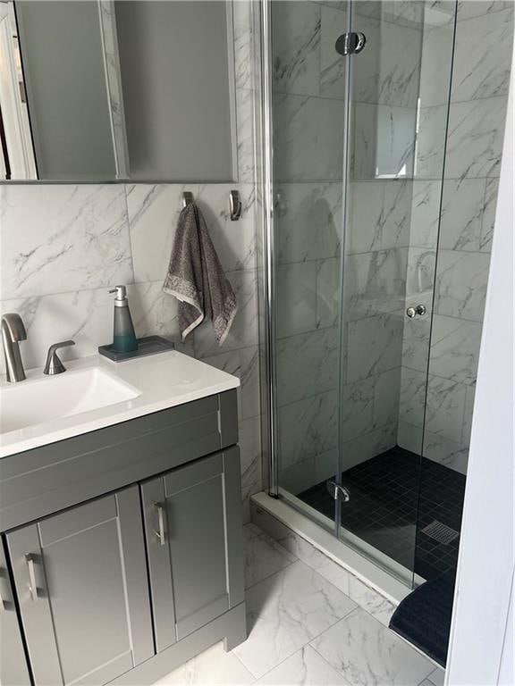 full bathroom with decorative backsplash, vanity, marble finish floor, and a shower stall