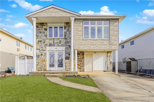 view of front facade with driveway, a front yard, and fence