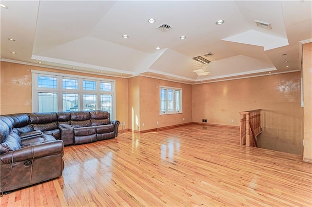 living room featuring visible vents, a raised ceiling, wood-type flooring, and crown molding