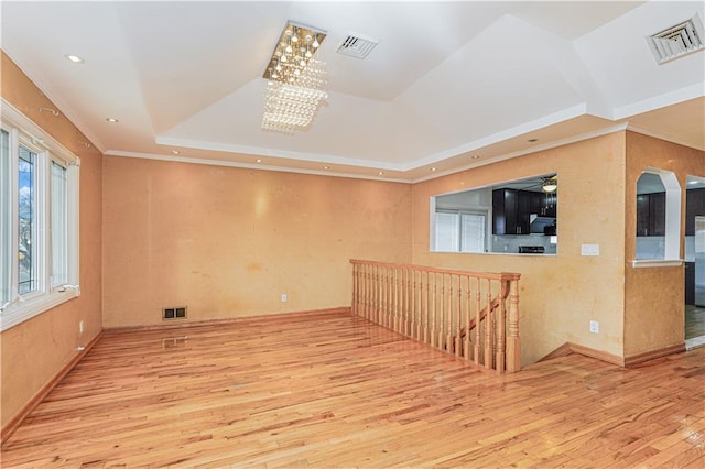 empty room featuring visible vents, a raised ceiling, and hardwood / wood-style flooring