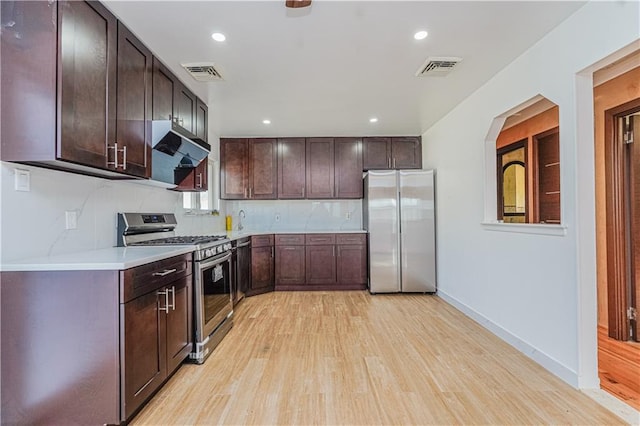 kitchen with visible vents, dark brown cabinets, light wood-style floors, under cabinet range hood, and appliances with stainless steel finishes