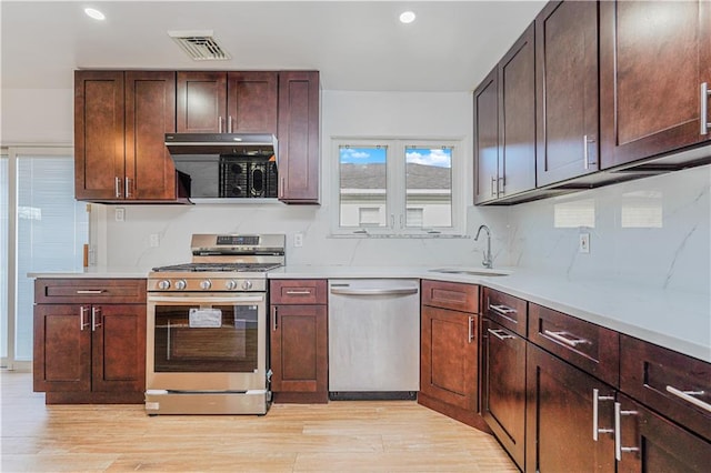 kitchen with a sink, visible vents, light wood-style floors, and appliances with stainless steel finishes