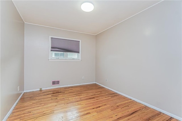 empty room featuring visible vents, baseboards, light wood-style floors, and ornamental molding