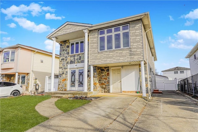 view of front facade featuring stone siding, french doors, a front lawn, and a gate