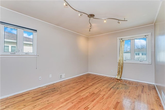 unfurnished room featuring light wood-style flooring, baseboards, visible vents, and a wealth of natural light