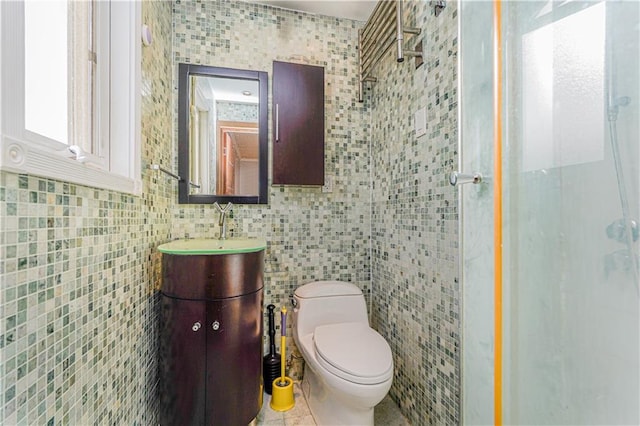 bathroom with tile patterned floors, toilet, a stall shower, tile walls, and vanity