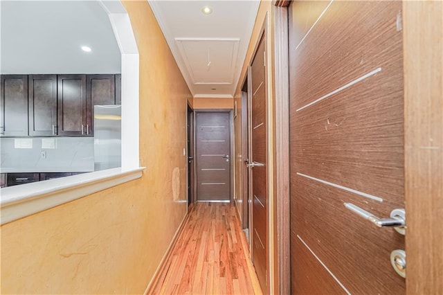 corridor with light wood finished floors, attic access, and ornamental molding