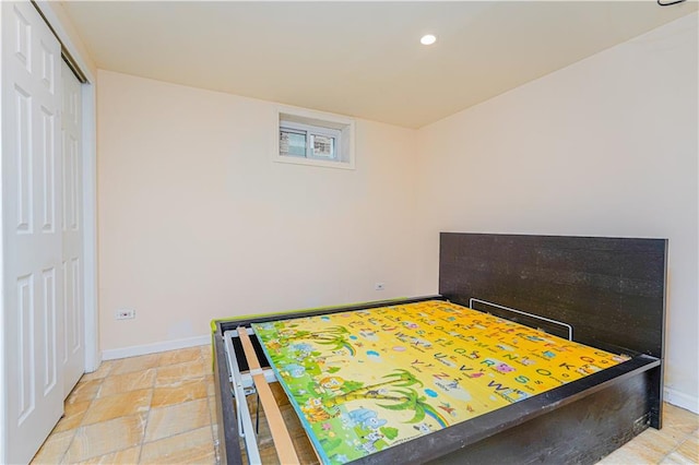 bedroom with recessed lighting, stone finish flooring, baseboards, and a closet