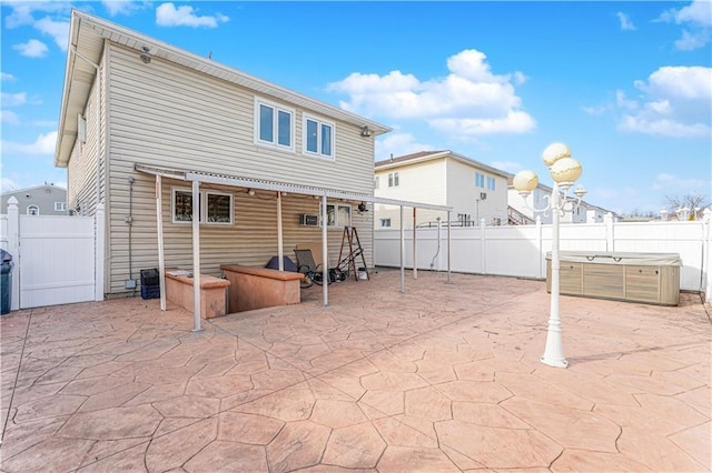 back of house with a patio area, a fenced backyard, and a hot tub