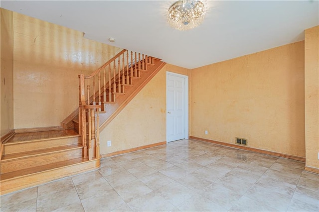 staircase featuring a textured wall, visible vents, and baseboards