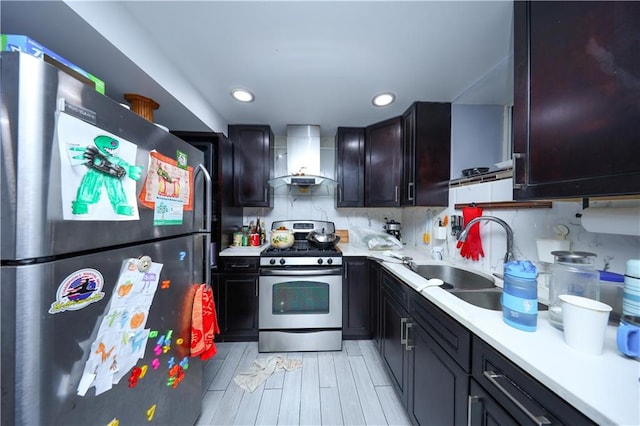 kitchen with wall chimney exhaust hood, wood tiled floor, stainless steel appliances, light countertops, and a sink