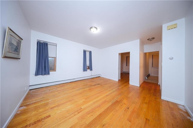 spare room with light wood-style floors, a baseboard radiator, and baseboards