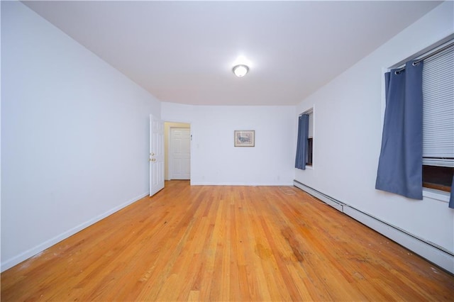 empty room featuring light wood-type flooring, a baseboard radiator, and baseboards