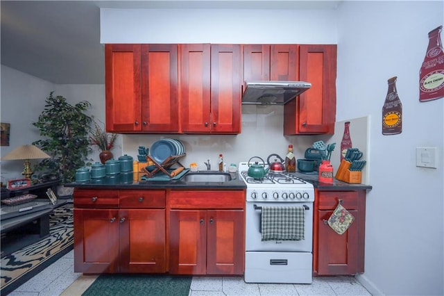 kitchen featuring light speckled floor, white gas stove, dark countertops, dark brown cabinets, and under cabinet range hood