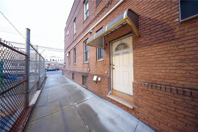 doorway to property with fence and brick siding