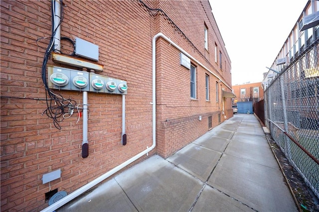 view of property exterior featuring brick siding and fence